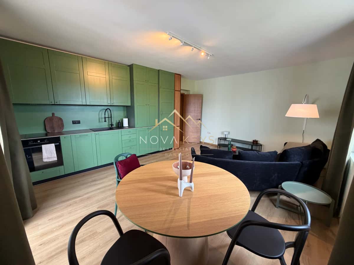 Open-plan kitchen living room with green cabinets and round dining table, two-bedroom apartment for sale in Pirin Golf.