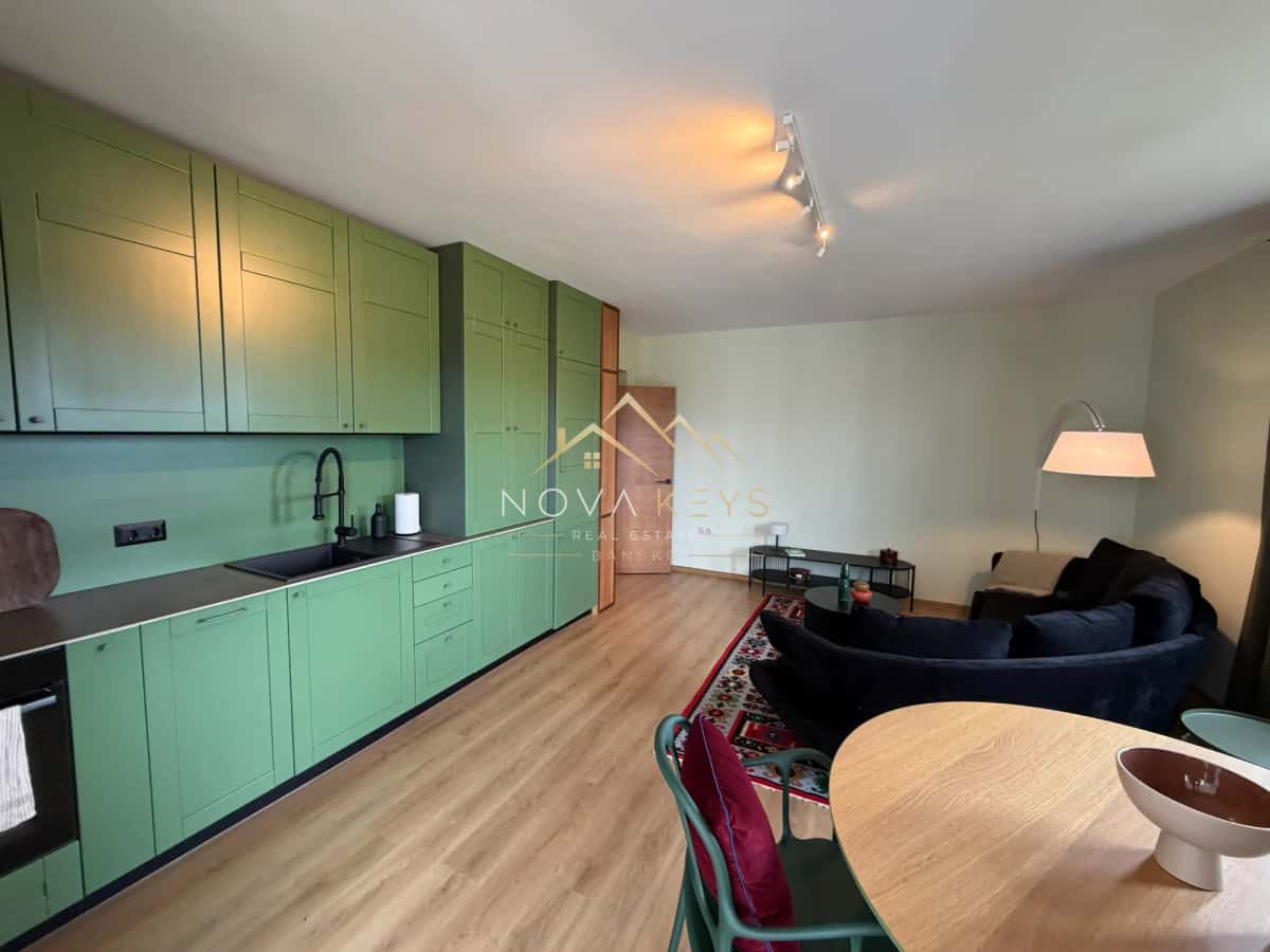 Open-plan living room and kitchen with green cabinets, two-bedroom apartment for sale in Pirin Golf.