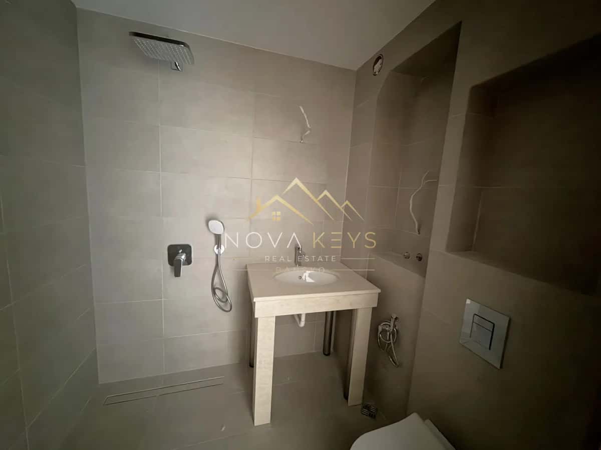 Tiled bathroom with shower and small sink, two-bedroom apartment for sale in the Bansko ski area.