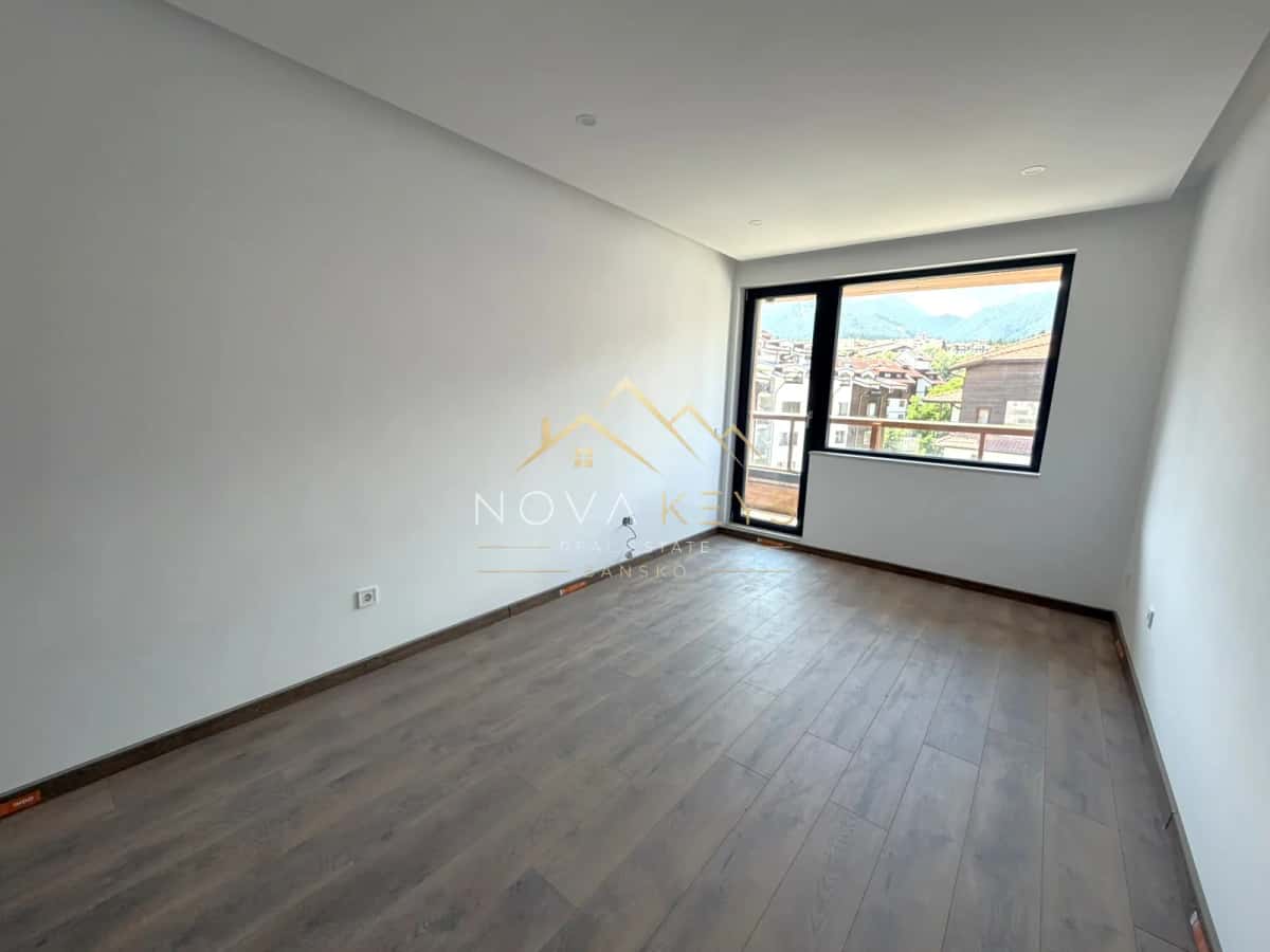 empty room with wood-look floor and large window, two-bedroom apartment for sale in the Bansko ski area.