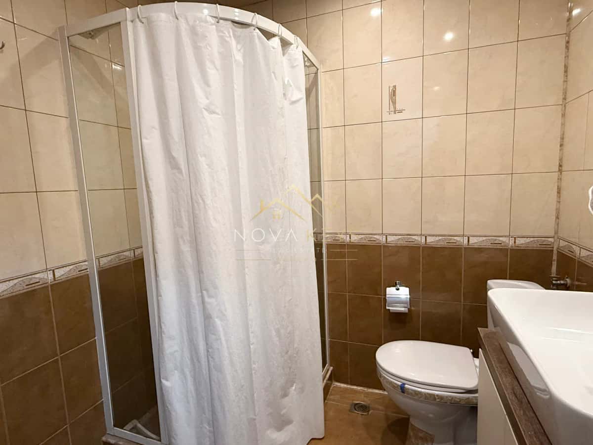 Bathroom with shower curtain and toilet, three-bedroom apartment for rent in Bansko centre.