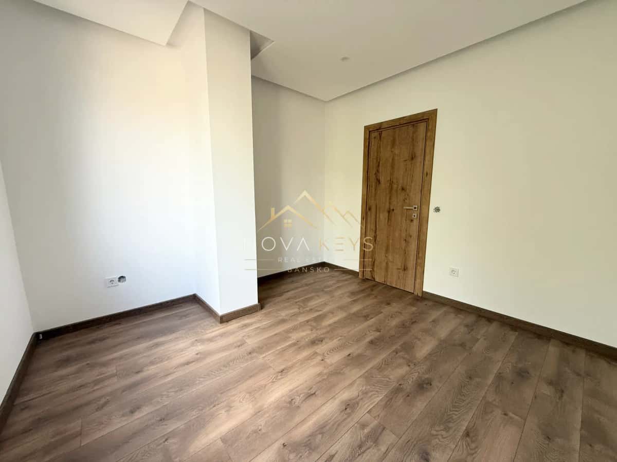 empty room with wood flooring and wooden door, three-bedroom apartment for sale in the Bansko ski area.