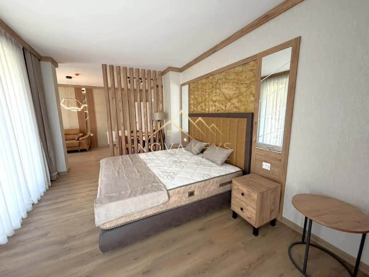 Modern bedroom with double bed and wooden accent wall, studio for sale in the Bansko ski area.