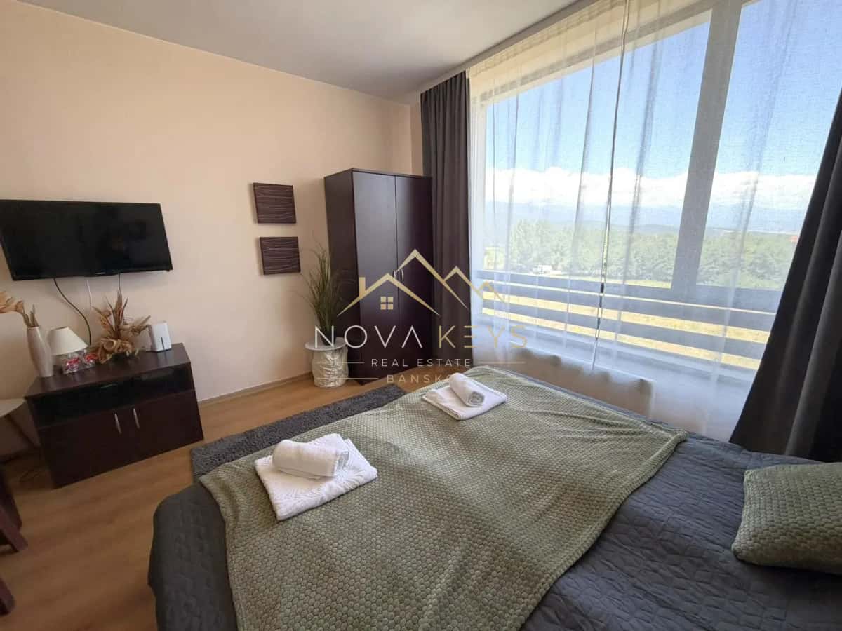 Bedroom with bed, TV, and large window, studio for rent in Razlog.
