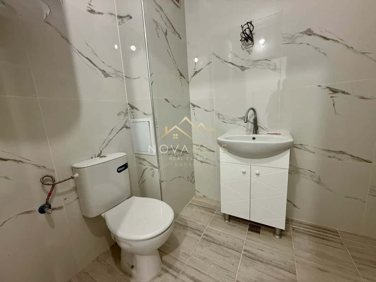 Small tiled bathroom with toilet and sink vanity, two-bedroom apartment for sale in Bansko centre.