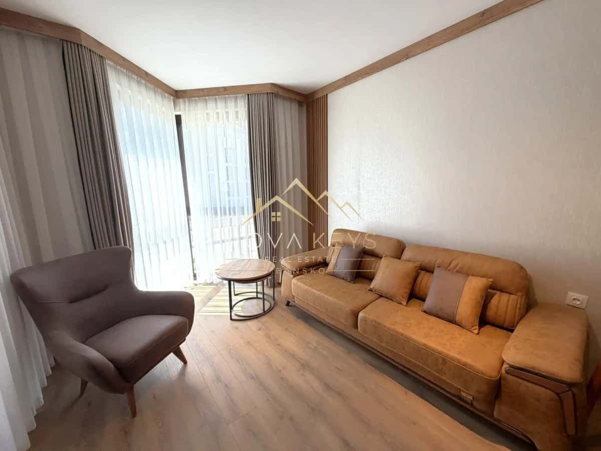 living room with tan sofa and gray armchair, two-bedroom apartment for sale in the Bansko ski area.