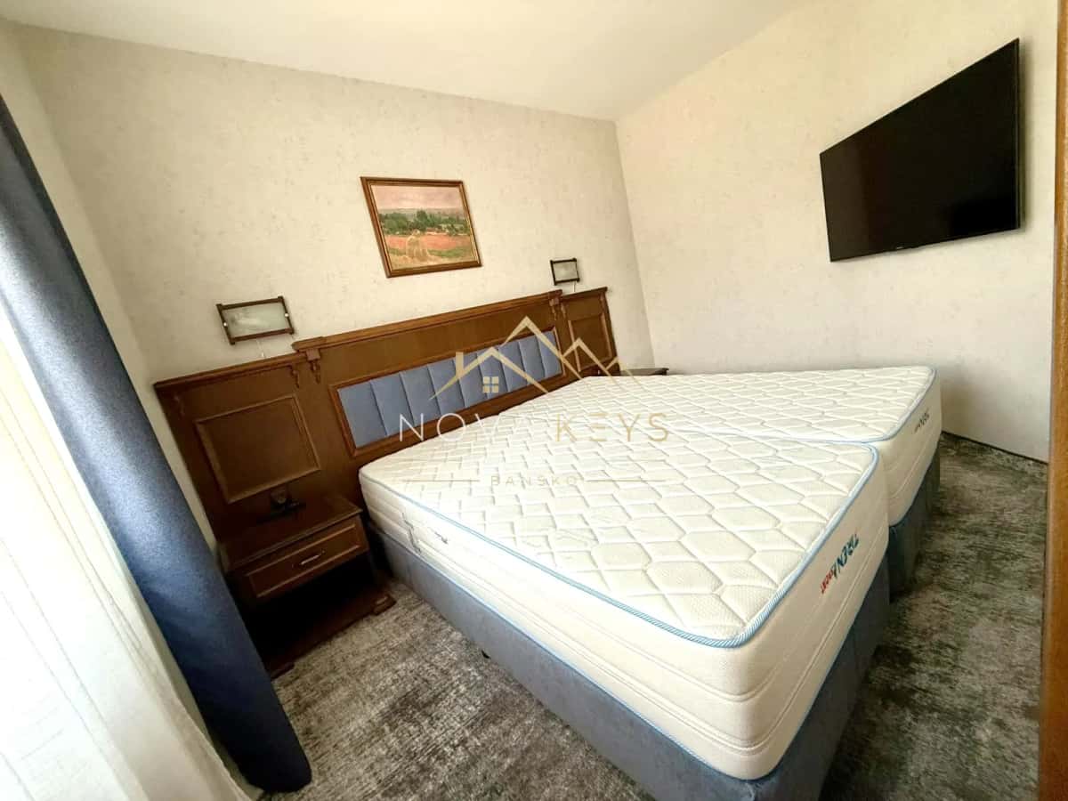 small bedroom with double bed and wall-mounted TV, two-bedroom apartment for sale in the Bansko ski area.