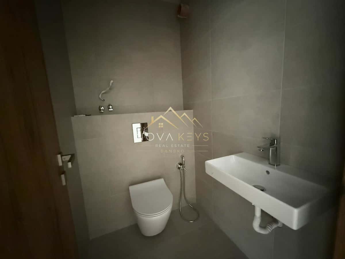 Modern bathroom with wall-mounted toilet and sink, three-bedroom apartment for sale in the Bansko ski area.