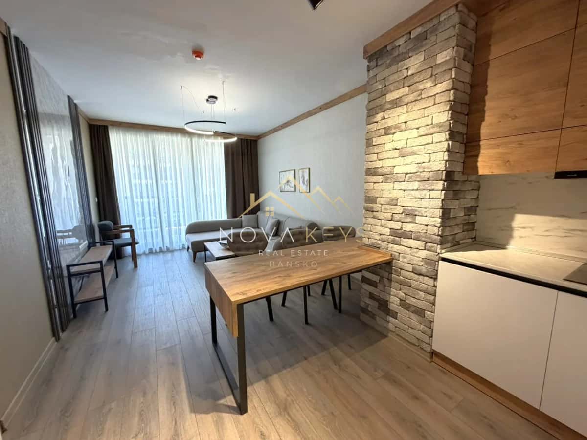 Open-plan living room with dining table and stone column, three-bedroom apartment for sale in the Bansko ski area.