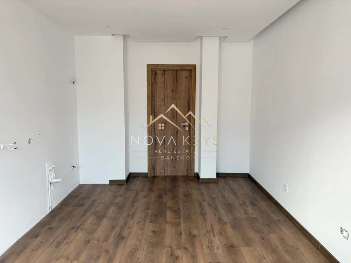Empty room with wood floor and wooden door, two-bedroom apartment for sale in the Bansko ski area.