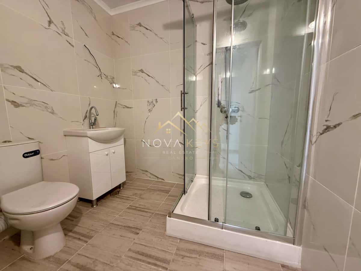 modern bathroom with toilet, vanity, and glass shower, two-bedroom apartment for sale in Bansko.