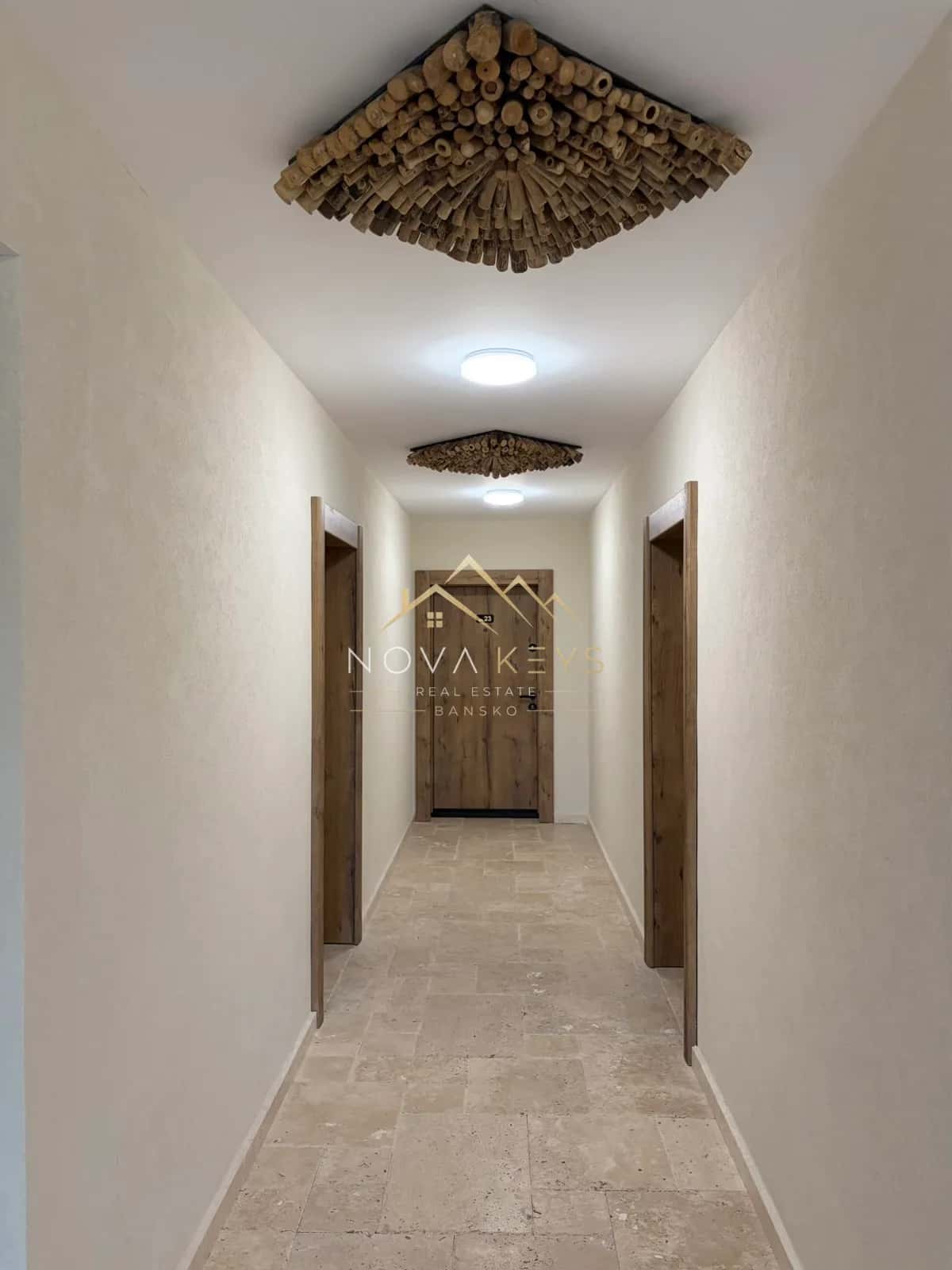narrow hallway with stone floor and wooden doors, two-bedroom apartment for sale in the Bansko ski area.