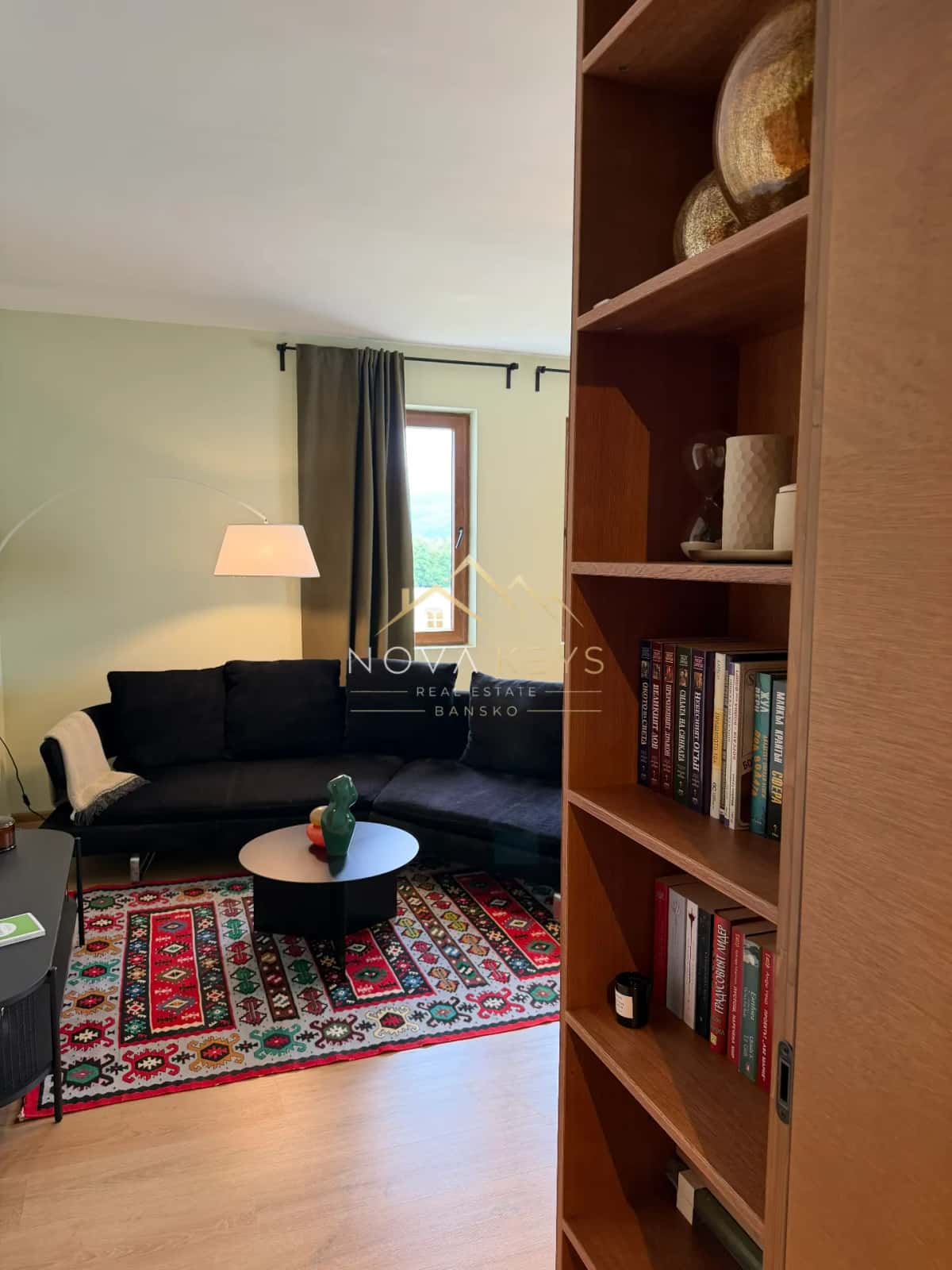Living room with black sofa and bookshelf, two-bedroom apartment for sale in Pirin Golf.
