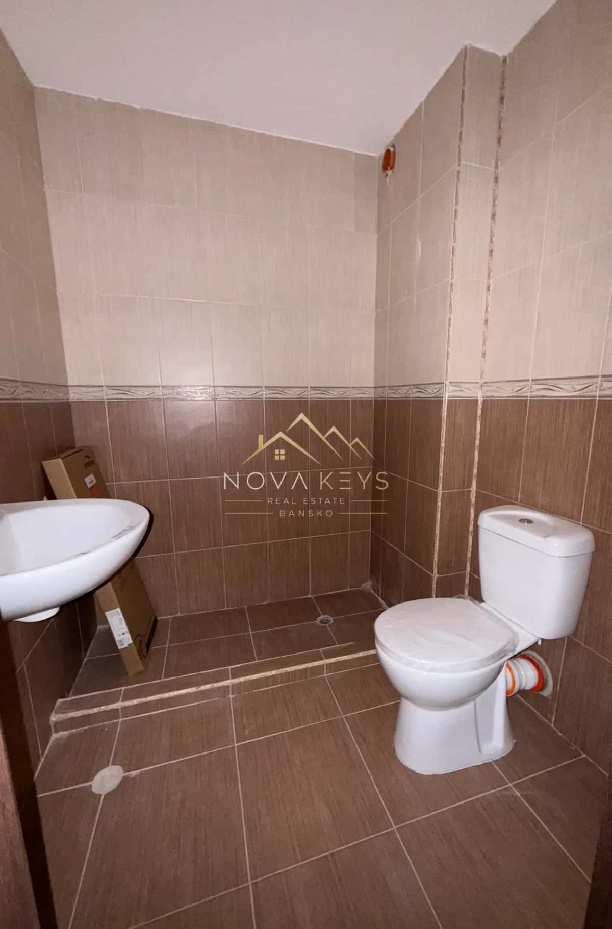 small tiled bathroom with sink and toilet, studio for sale in the Bansko ski area.