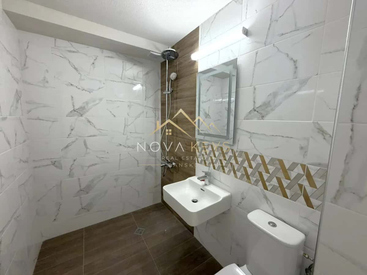 Modern bathroom with walk-in shower and wall-mounted sink, three-bedroom apartment for sale in the Bansko ski area.