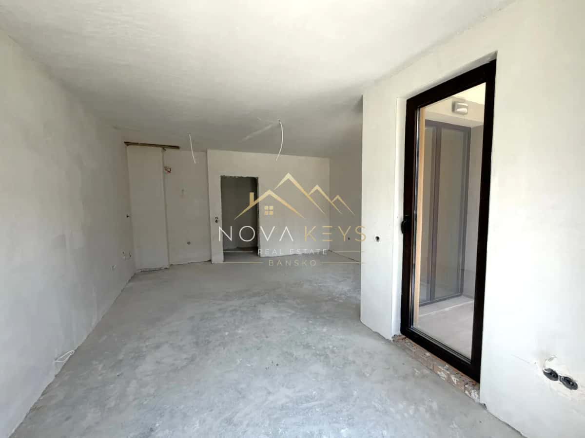 unfinished room with concrete floor and glass door, studio for sale in the Bansko ski area.
