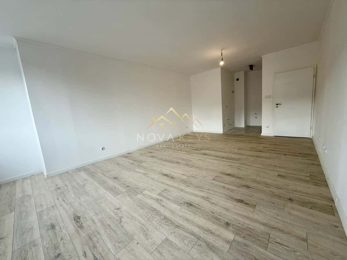 Empty room with wood-look flooring and white walls, two-bedroom apartment for sale in Bansko.
