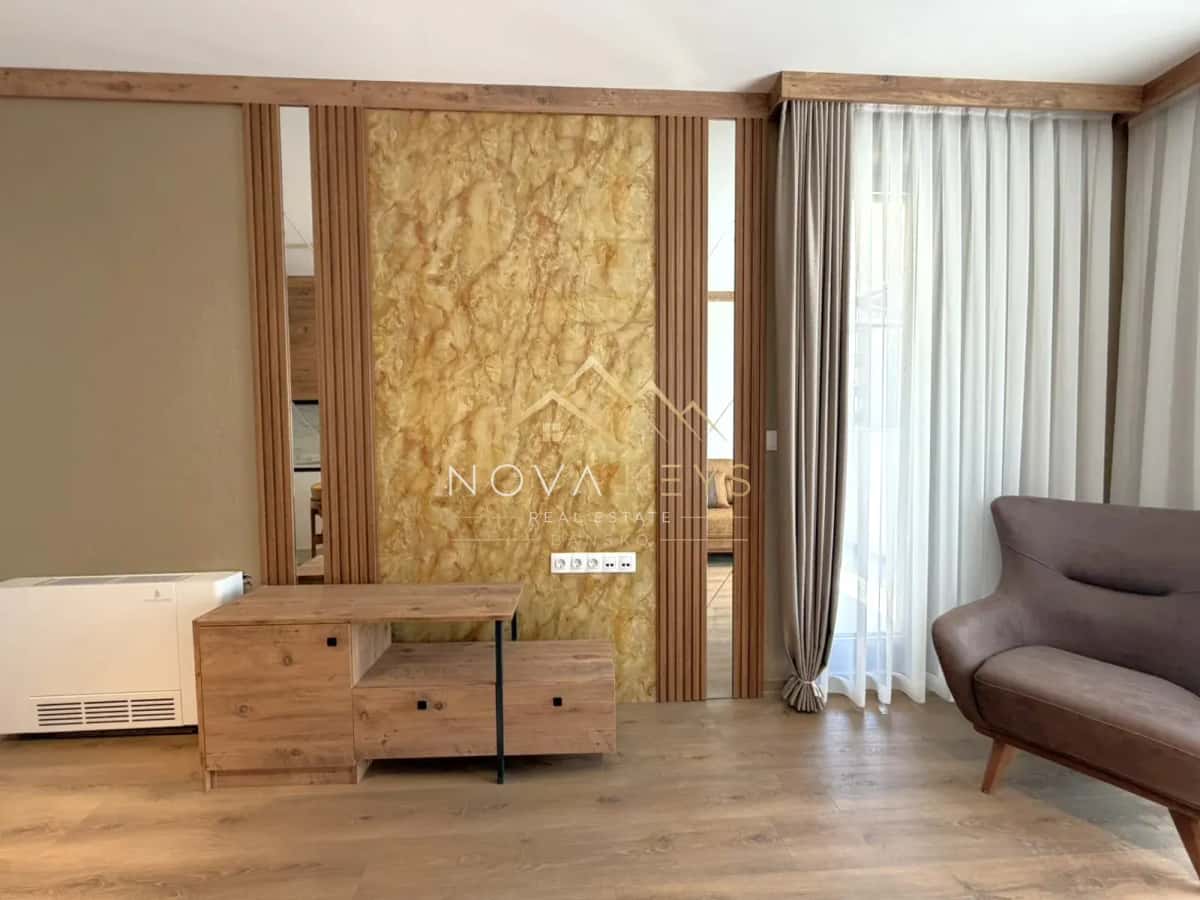 Living room with feature wall and curtains, two-bedroom apartment for sale in the Bansko ski area.