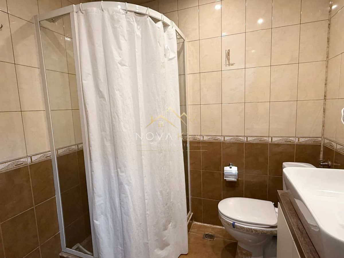 Bathroom with shower curtain and toilet, three-bedroom apartment for rent in Bansko centre.