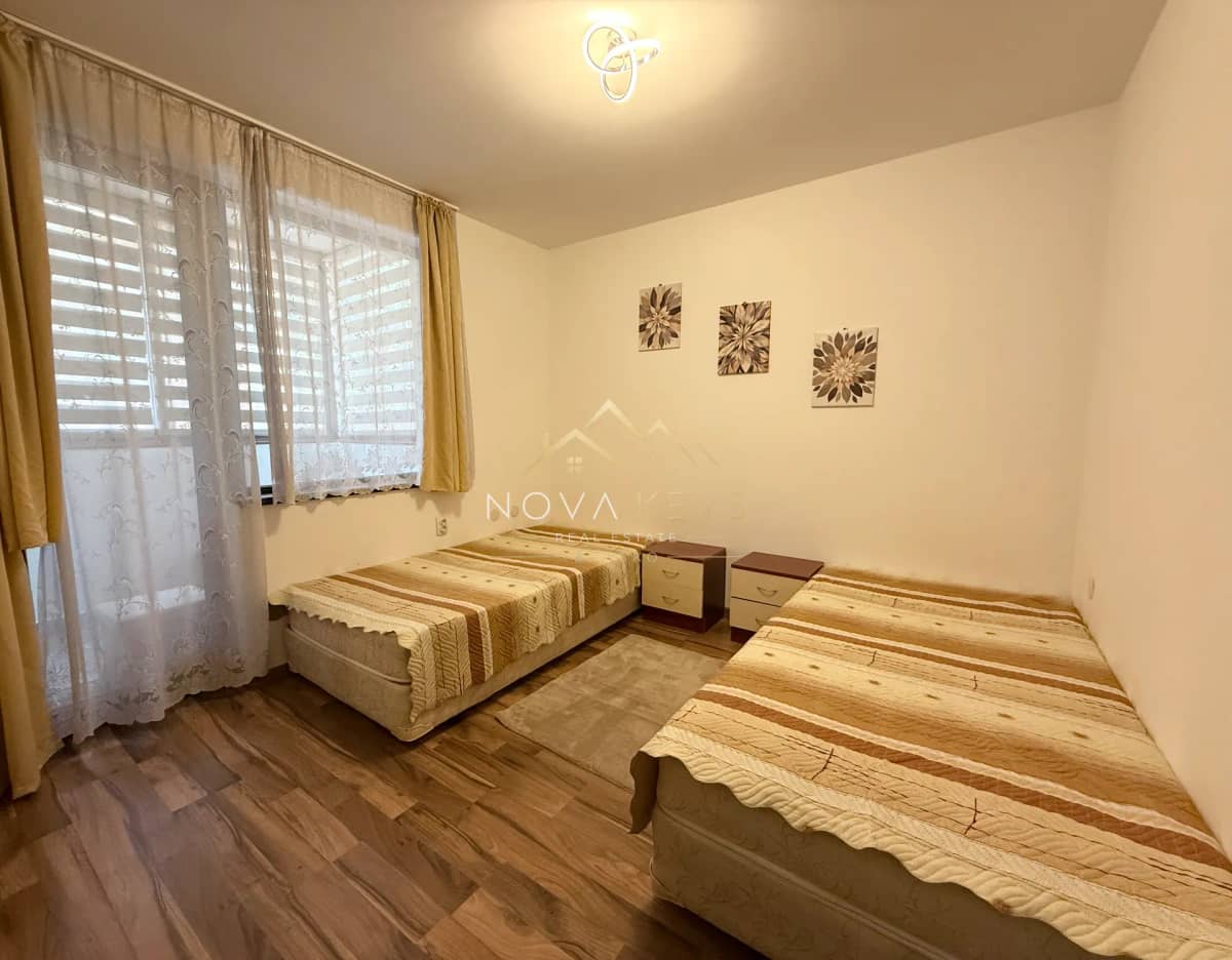 small bedroom with two single beds and window curtains, three-bedroom apartment for rent in Bansko centre.