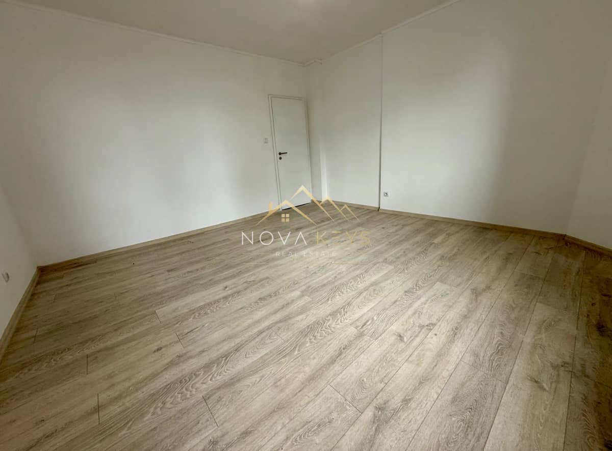 Empty room with wood flooring and white door, two-bedroom apartment for sale in Bansko centre.