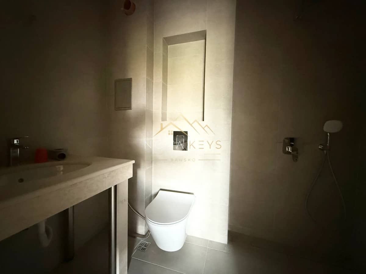Bathroom with wall-mounted sink and toilet, three-bedroom apartment for sale in the Bansko ski area.