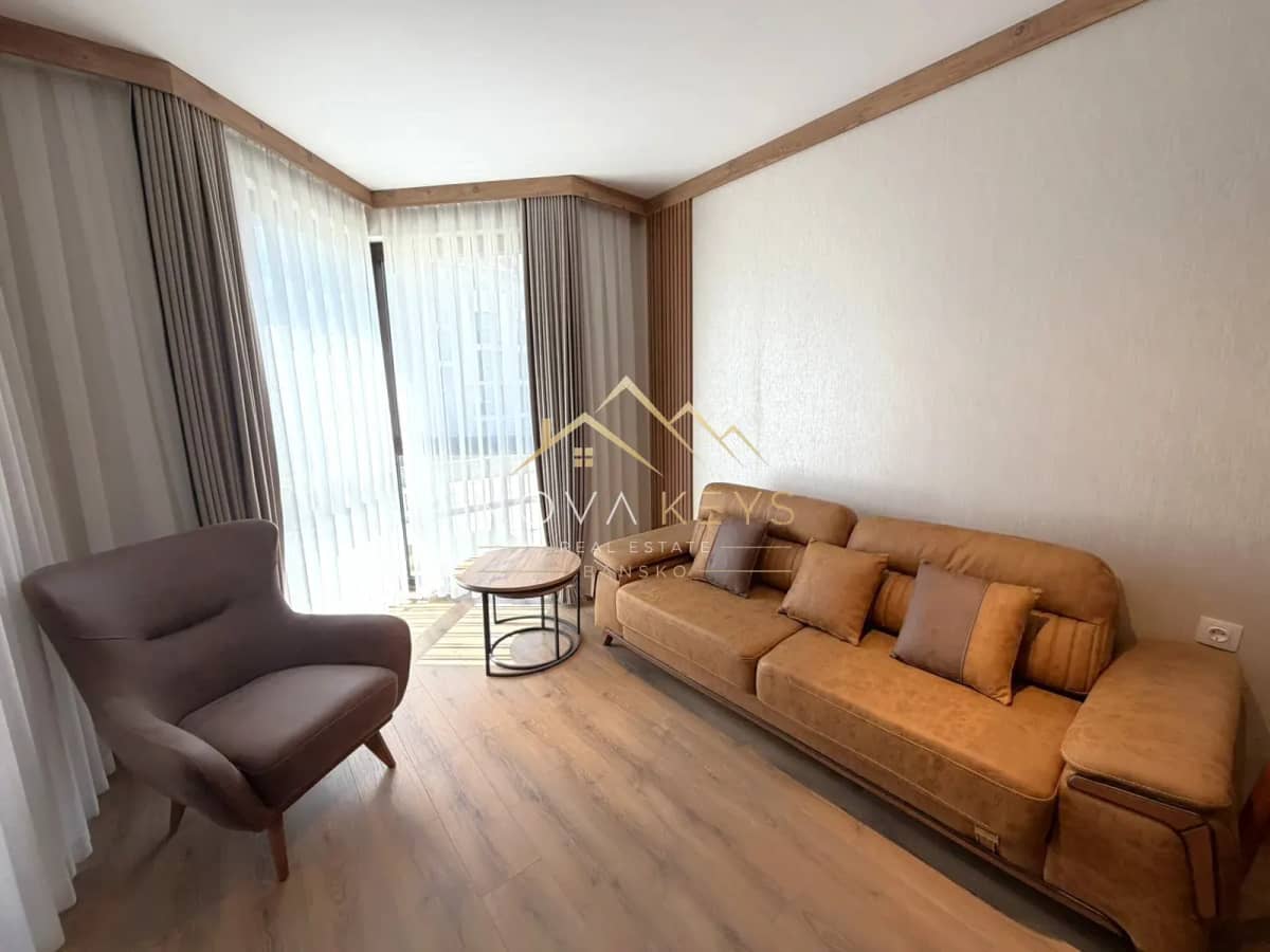 living room with tan sofa and gray armchair, two-bedroom apartment for sale in the Bansko ski area.