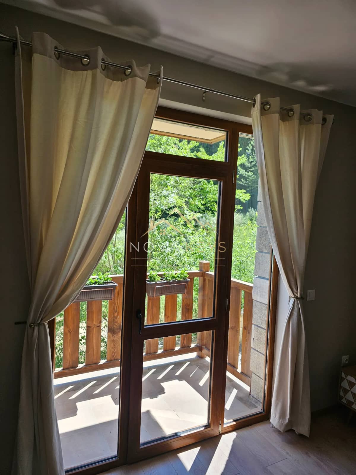 Wood-framed glass door with beige curtains, studio for sale in the Bansko ski area.