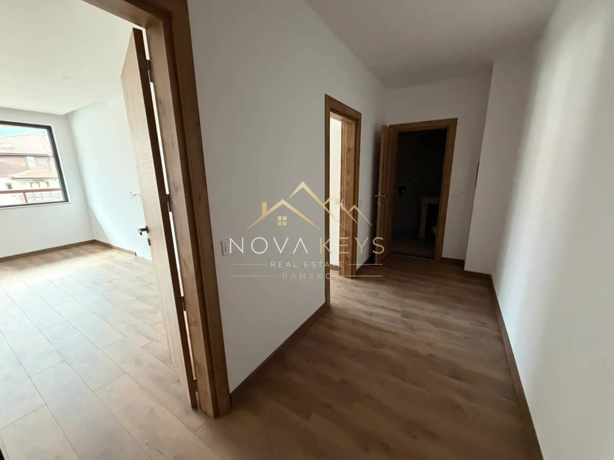 Empty hallway with wood flooring and open doorways, two-bedroom apartment for sale in the Bansko ski area.