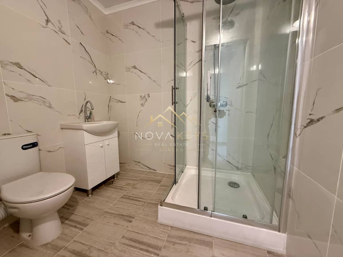 modern bathroom with toilet, vanity, and glass shower, two-bedroom apartment for sale in Bansko.