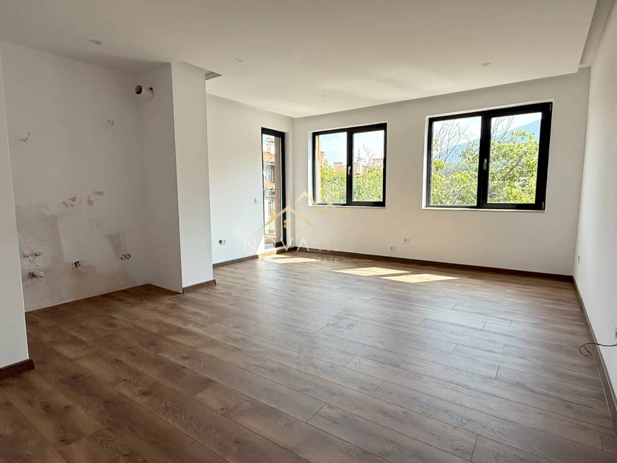 empty room with wood flooring and black-framed windows, three-bedroom apartment for sale in the Bansko ski area.