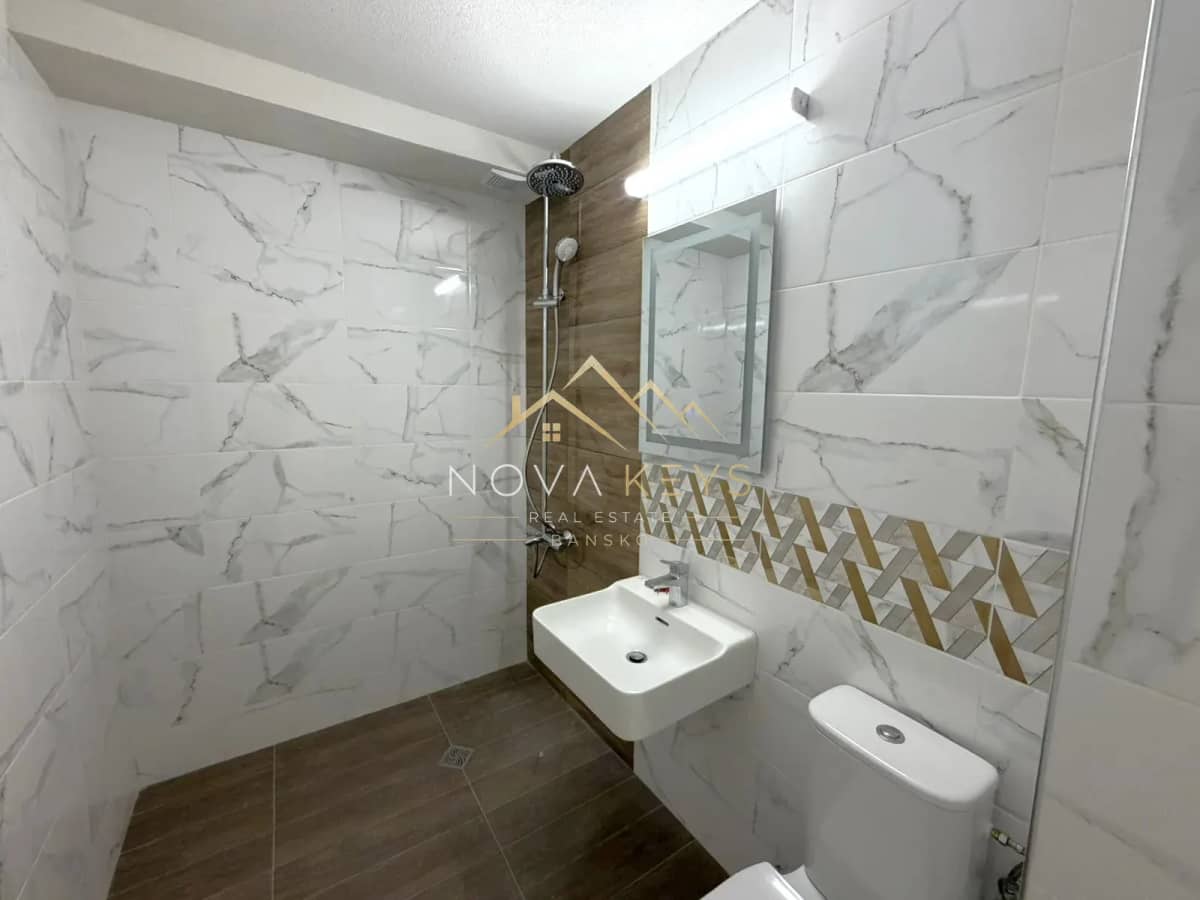 Modern bathroom with walk-in shower and wall-mounted sink, three-bedroom apartment for sale in the Bansko ski area.