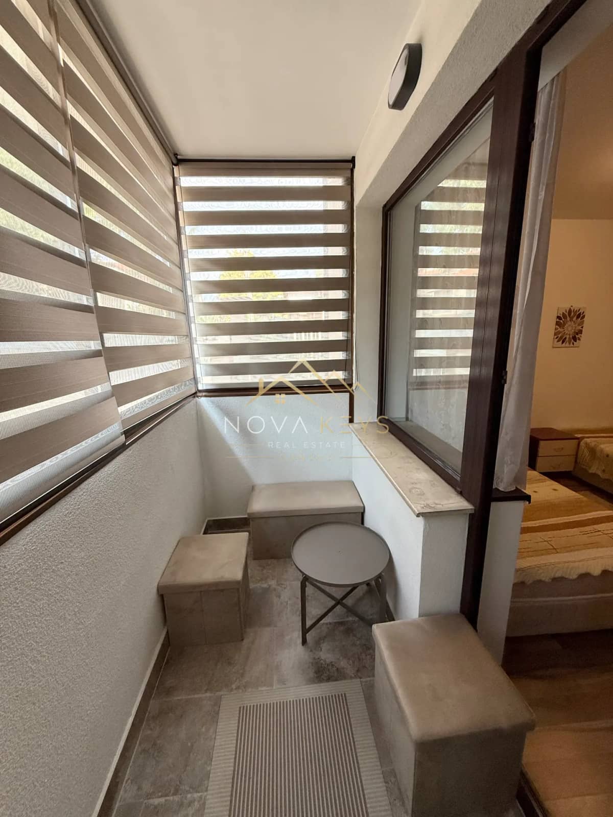 Enclosed balcony with blinds and small table, three-bedroom apartment for rent in Bansko centre.