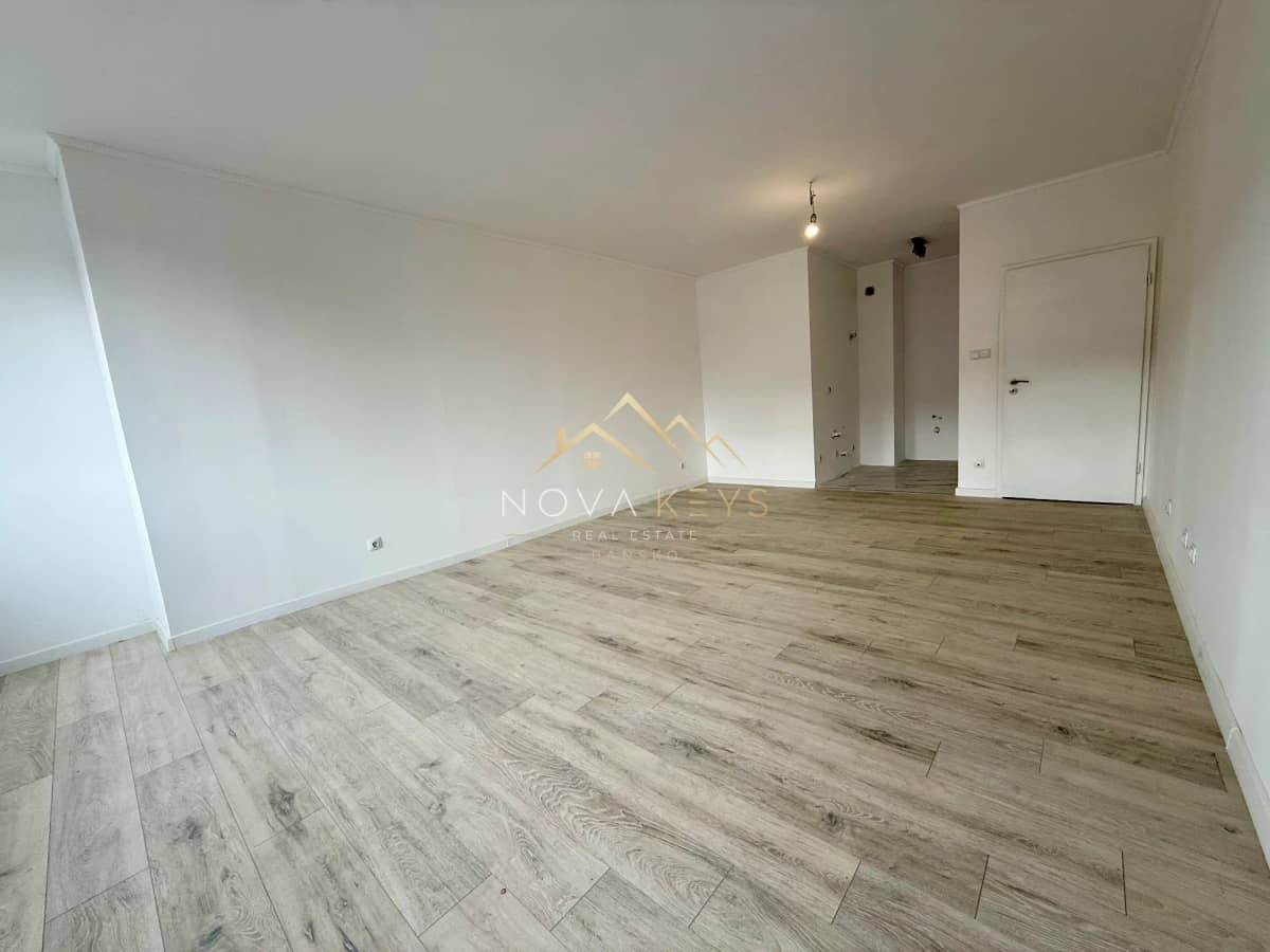 Empty room with wood-look flooring and white walls, two-bedroom apartment for sale in Bansko.