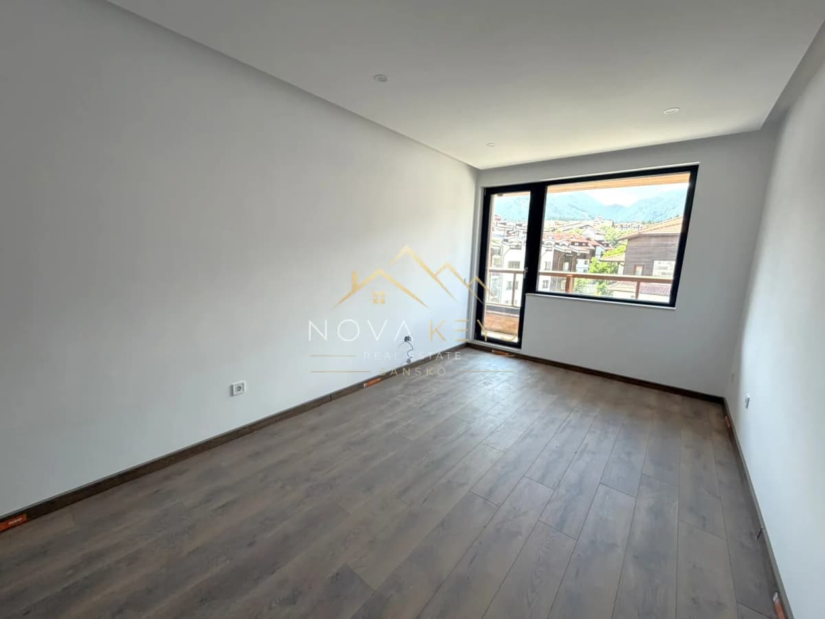 empty room with wood-look floor and large window, two-bedroom apartment for sale in the Bansko ski area.