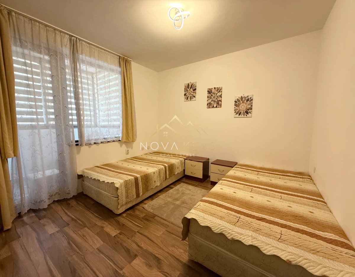 small bedroom with two single beds and window curtains, three-bedroom apartment for rent in Bansko centre.