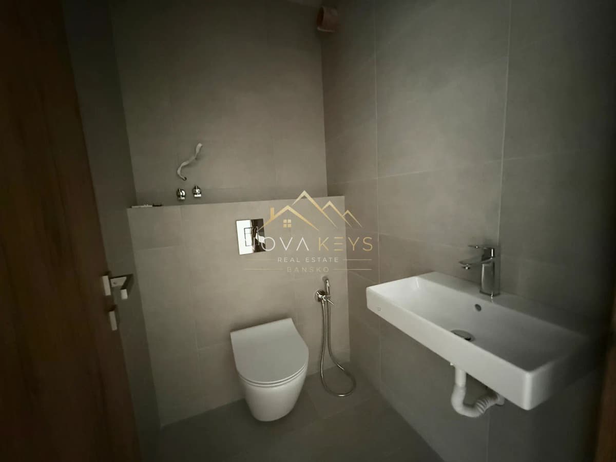 Modern bathroom with wall-mounted toilet and sink, three-bedroom apartment for sale in the Bansko ski area.