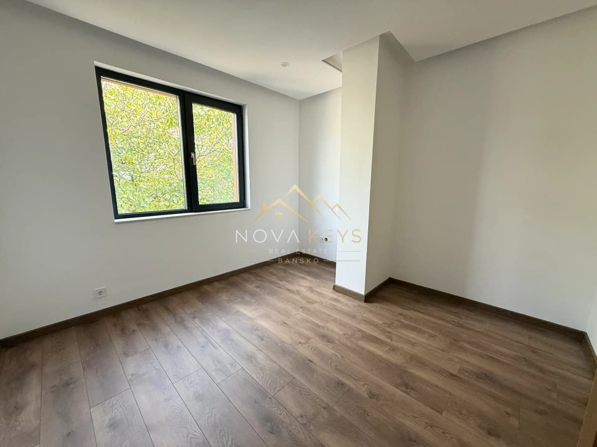 Empty room with window and wood flooring, three-bedroom apartment for sale in the Bansko ski area.