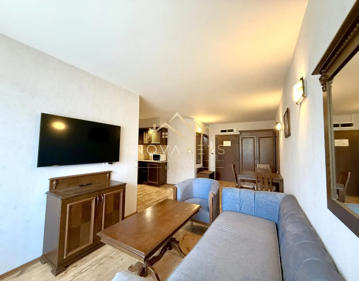 Living room with sofa, TV, and coffee table, two-bedroom apartment for sale in the Bansko ski area.