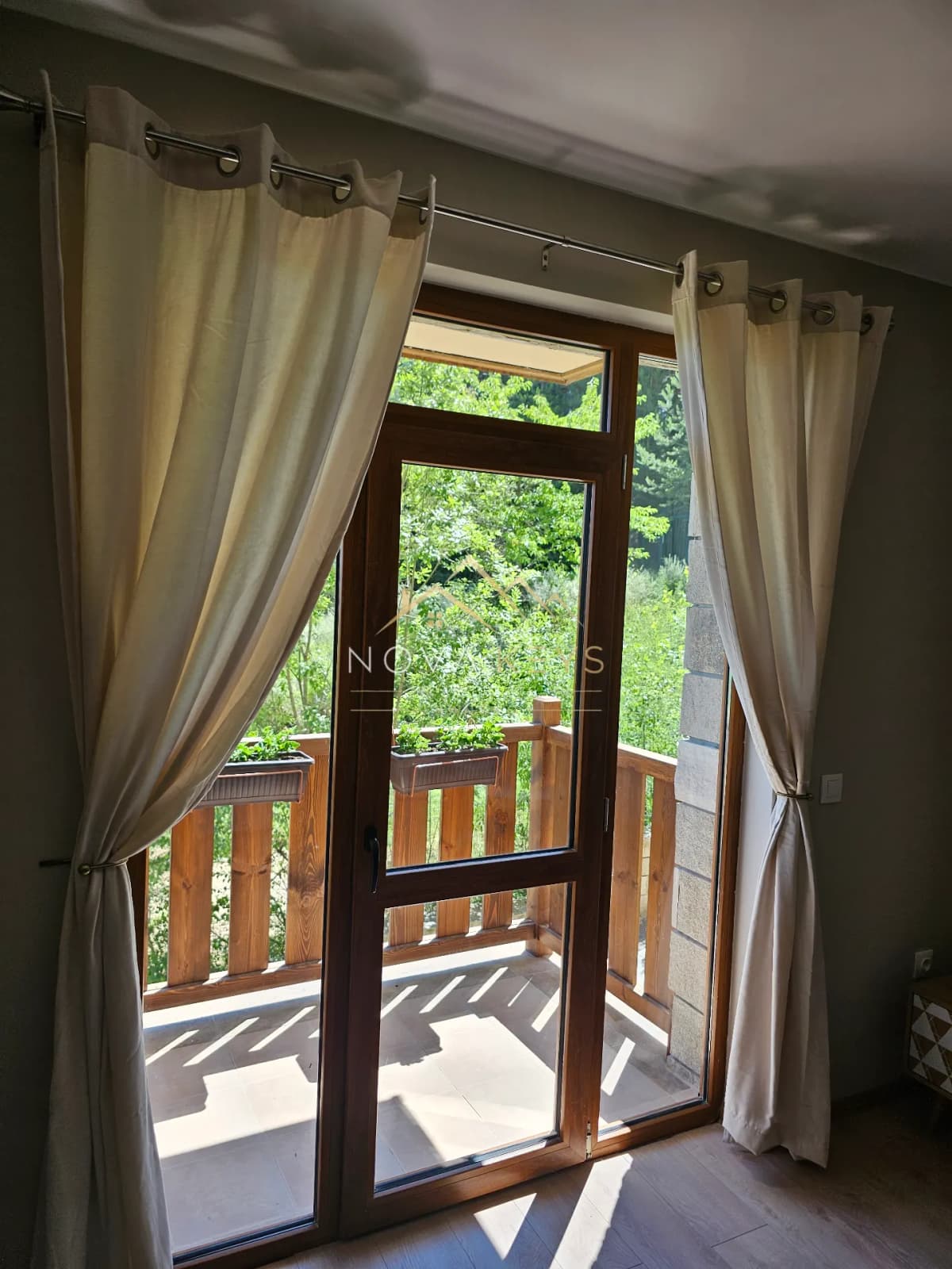 Wood-framed glass door with beige curtains, studio for sale in the Bansko ski area.