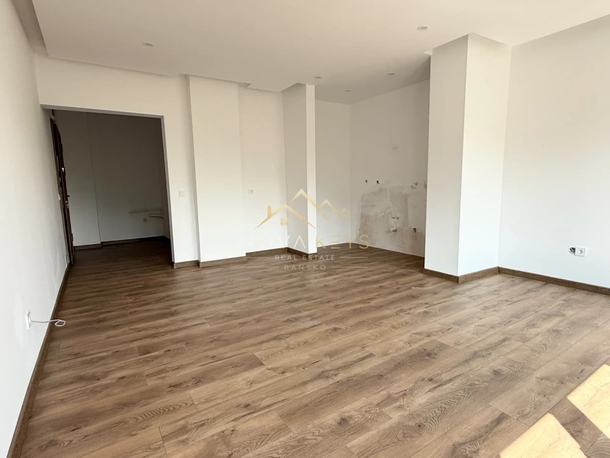 Empty room with wood flooring and recessed lights, three-bedroom apartment for sale in the Bansko ski area.