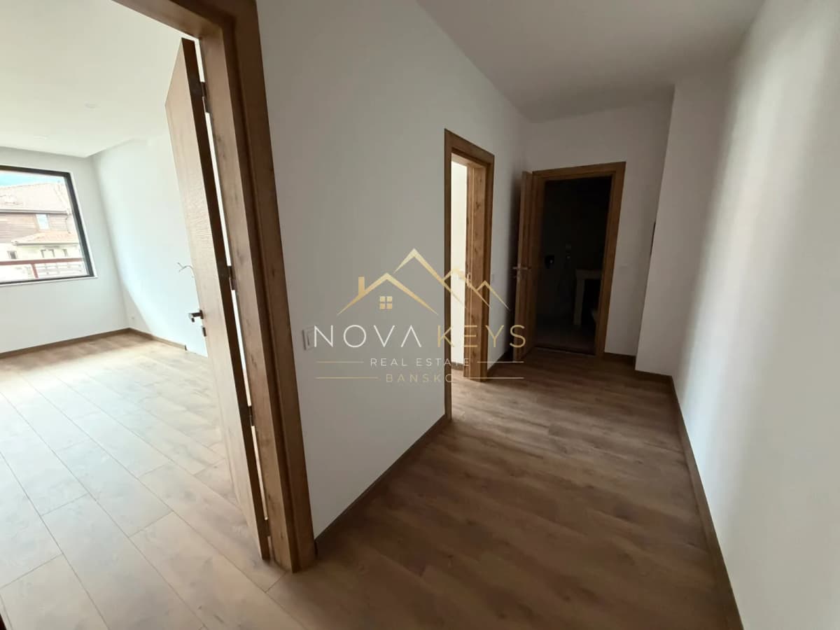 Empty hallway with wood flooring and open doorways, two-bedroom apartment for sale in the Bansko ski area.