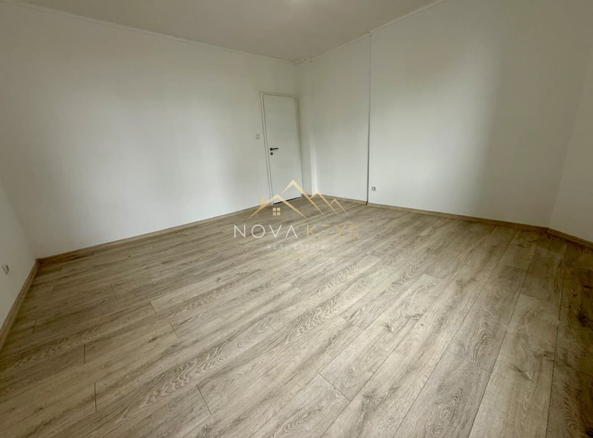 Празна стая с дървен под и бяла врата, двустаен апартамент за продажба в Bansko.