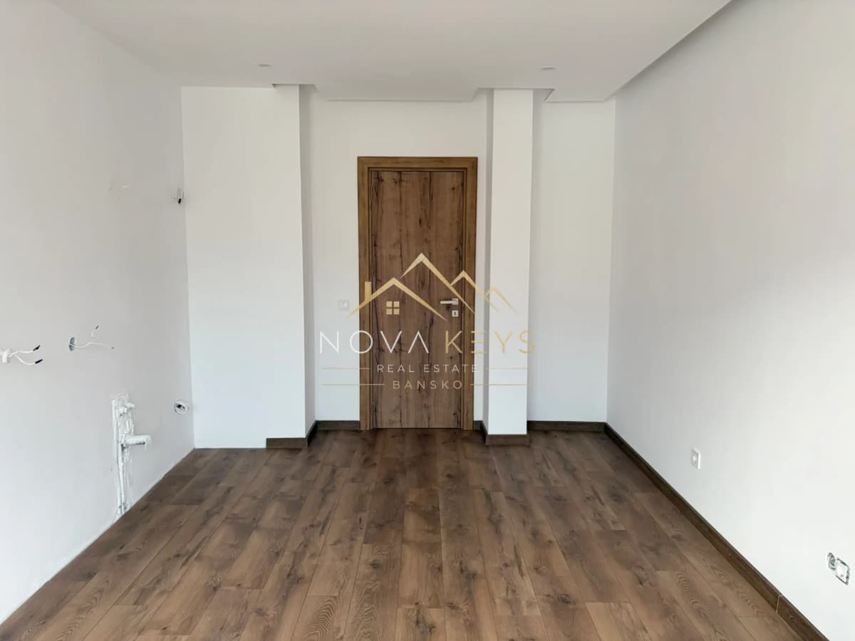 Empty room with wood floor and wooden door, two-bedroom apartment for sale in the Bansko ski area.