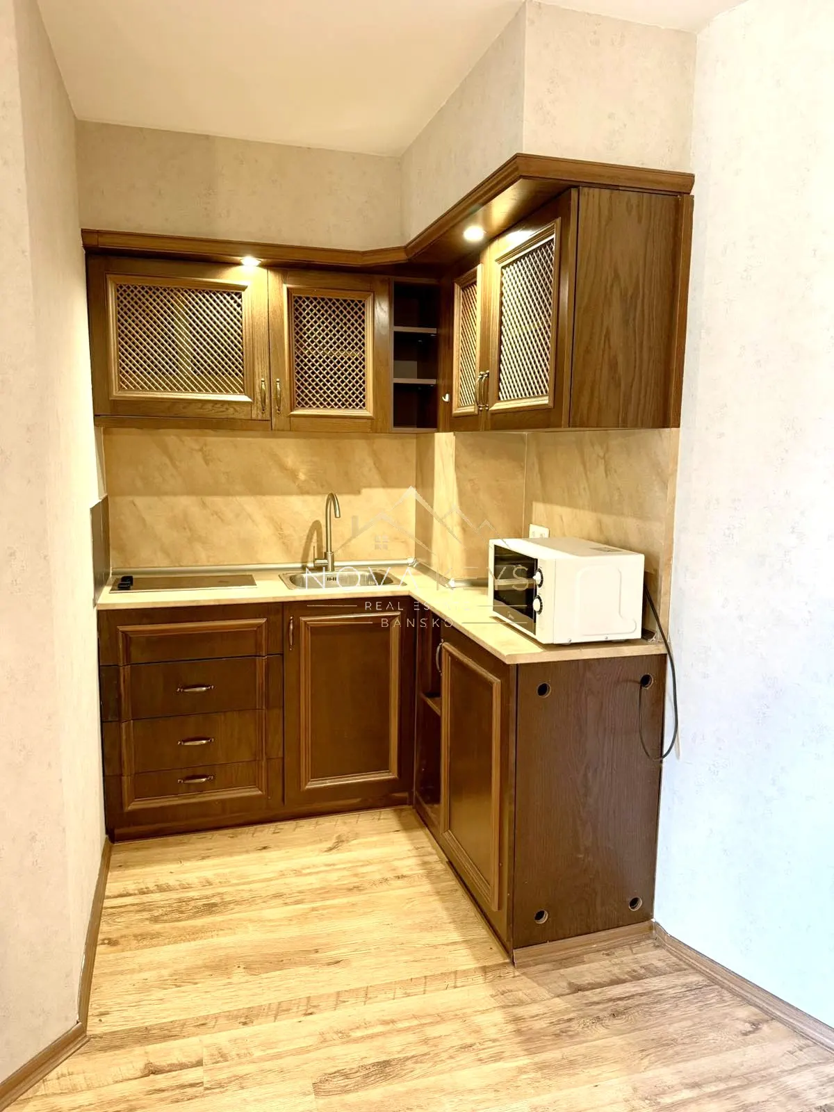 compact kitchen nook with wood cabinets and microwave, two-bedroom apartment for sale in the Bansko ski area.