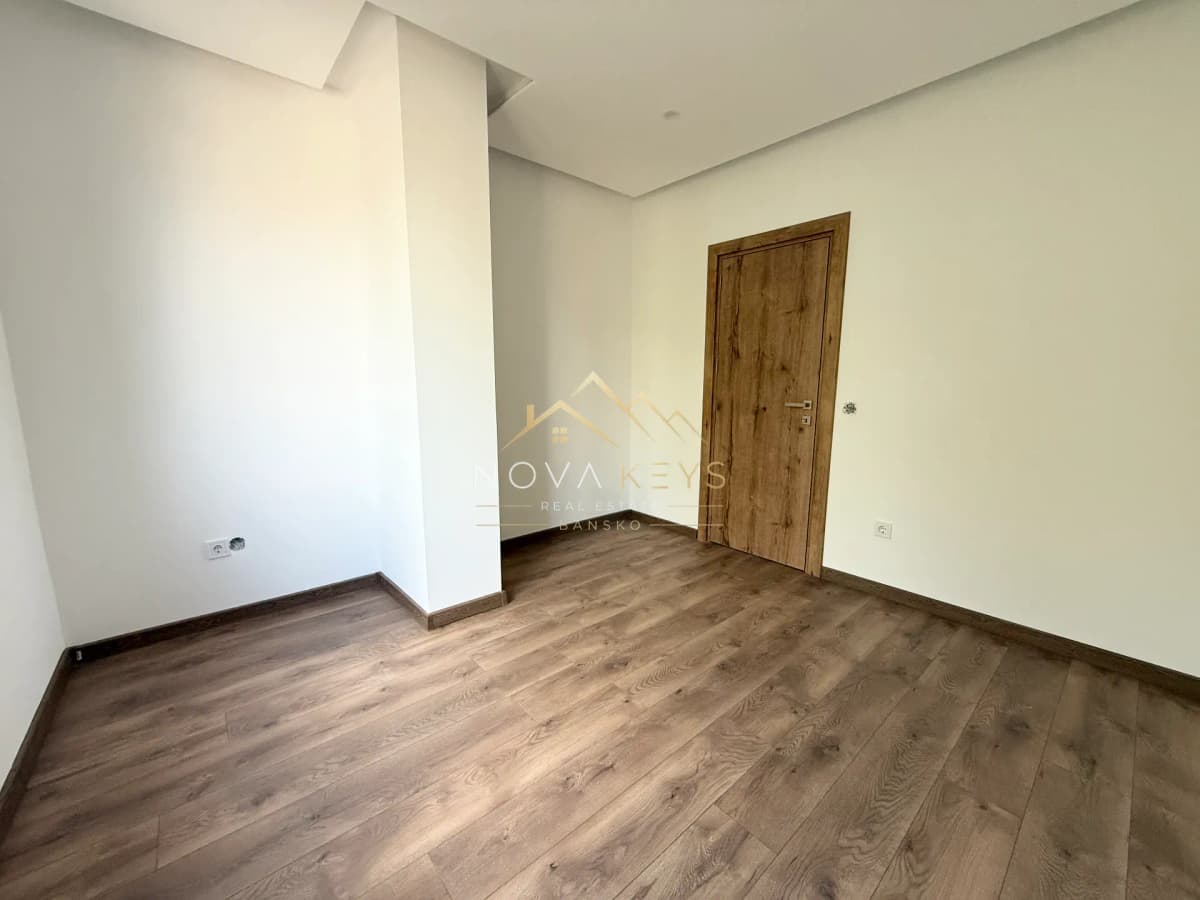 empty room with wood flooring and wooden door, three-bedroom apartment for sale in the Bansko ski area.