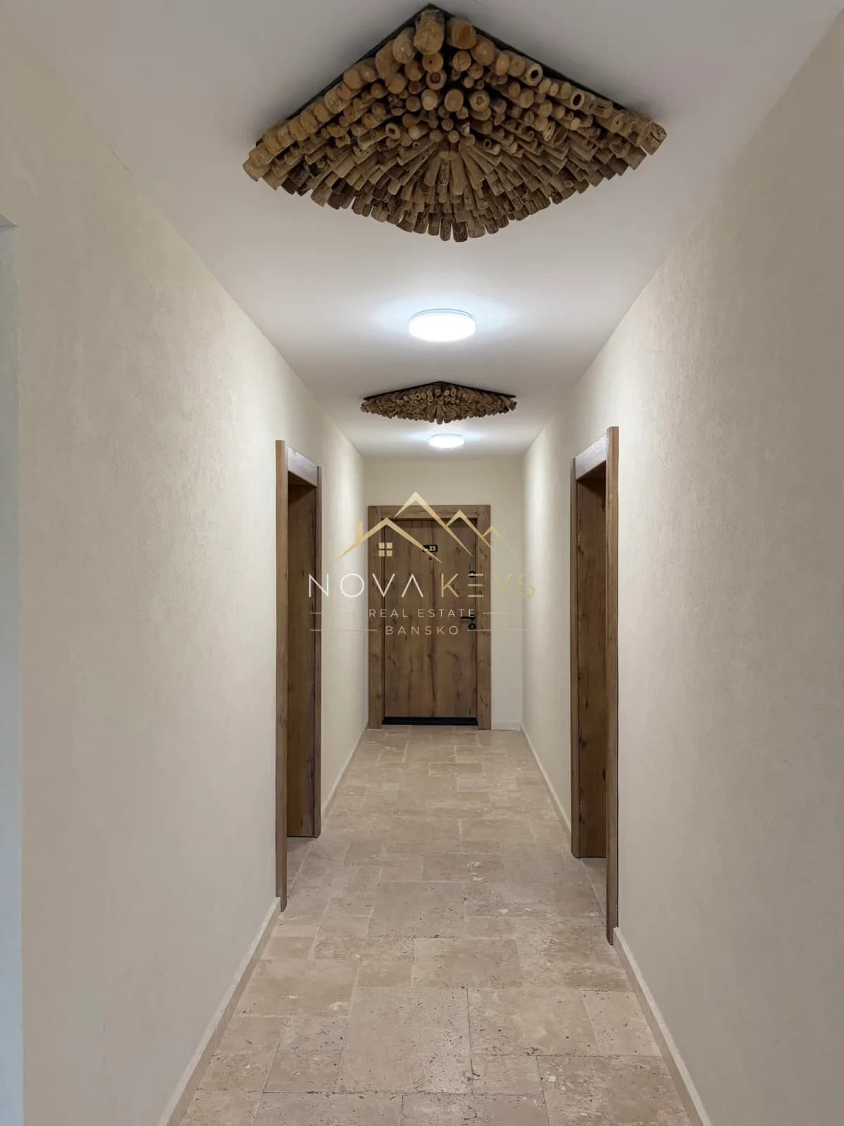 narrow hallway with stone floor and wooden doors, two-bedroom apartment for sale in the Bansko ski area.