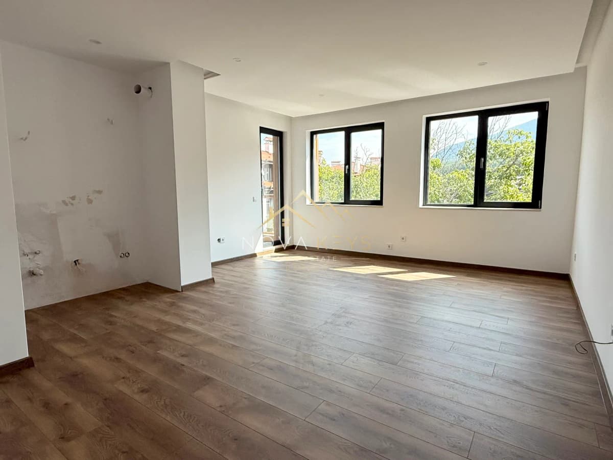 empty room with wood flooring and black-framed windows, three-bedroom apartment for sale in the Bansko ski area.