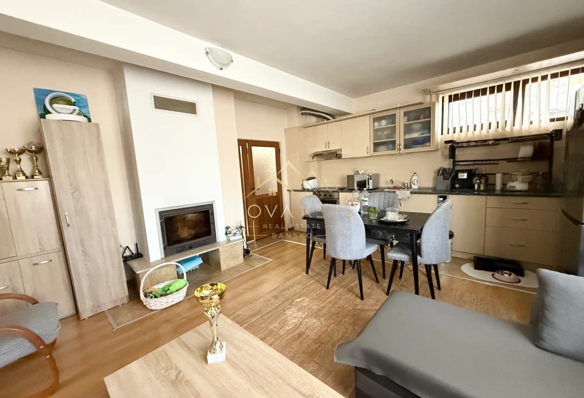 Open-plan living room kitchen with fireplace and dining table, three-bedroom apartment for sale in Bansko.