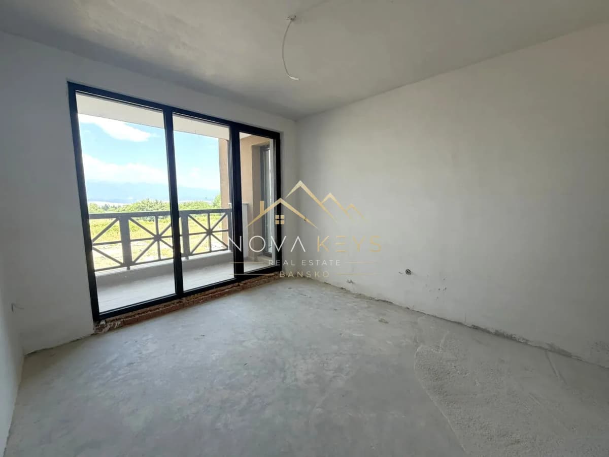 unfinished room with sliding glass doors and balcony, three-bedroom apartment for sale in the Bansko ski area.